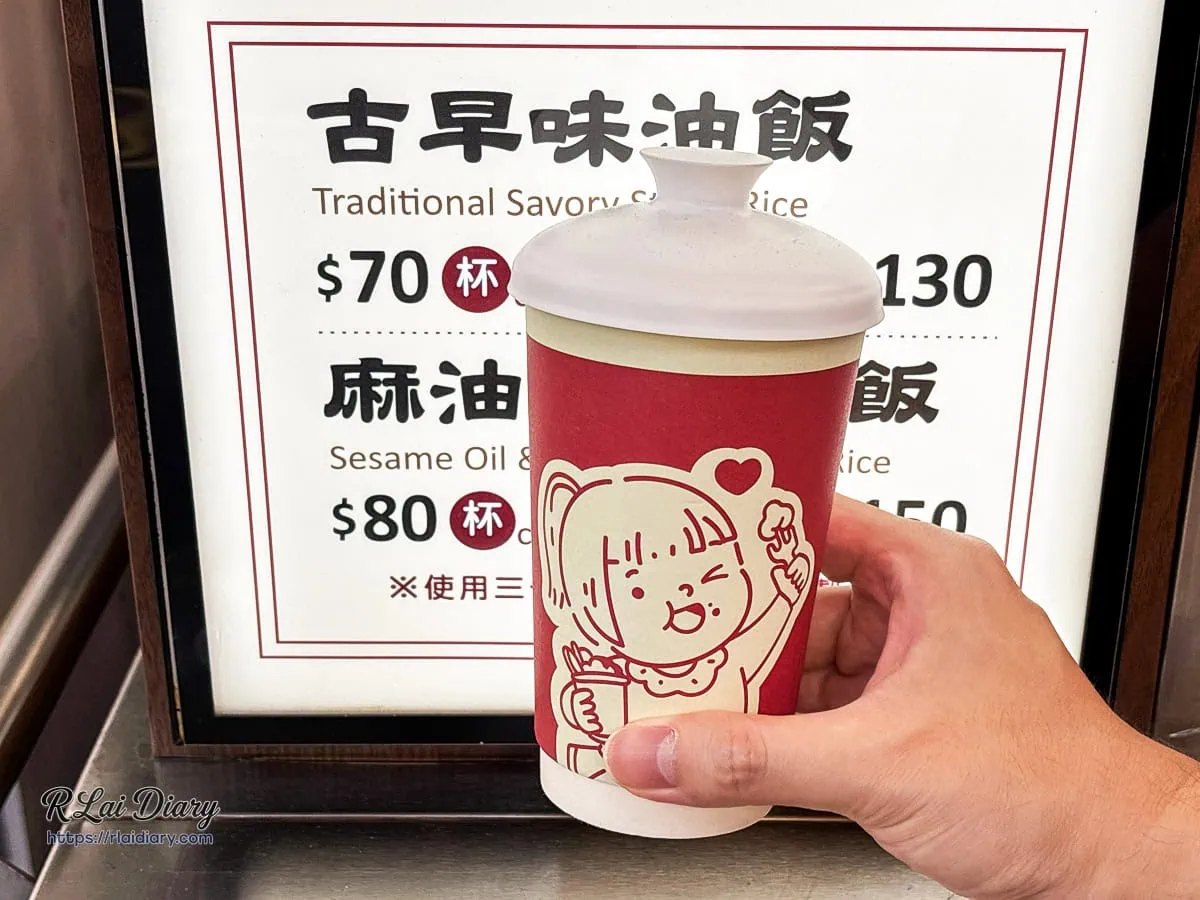 拿在手上的冠顗油飯一中店特色紙杯，杯身印有可愛插畫，適合邊走邊吃