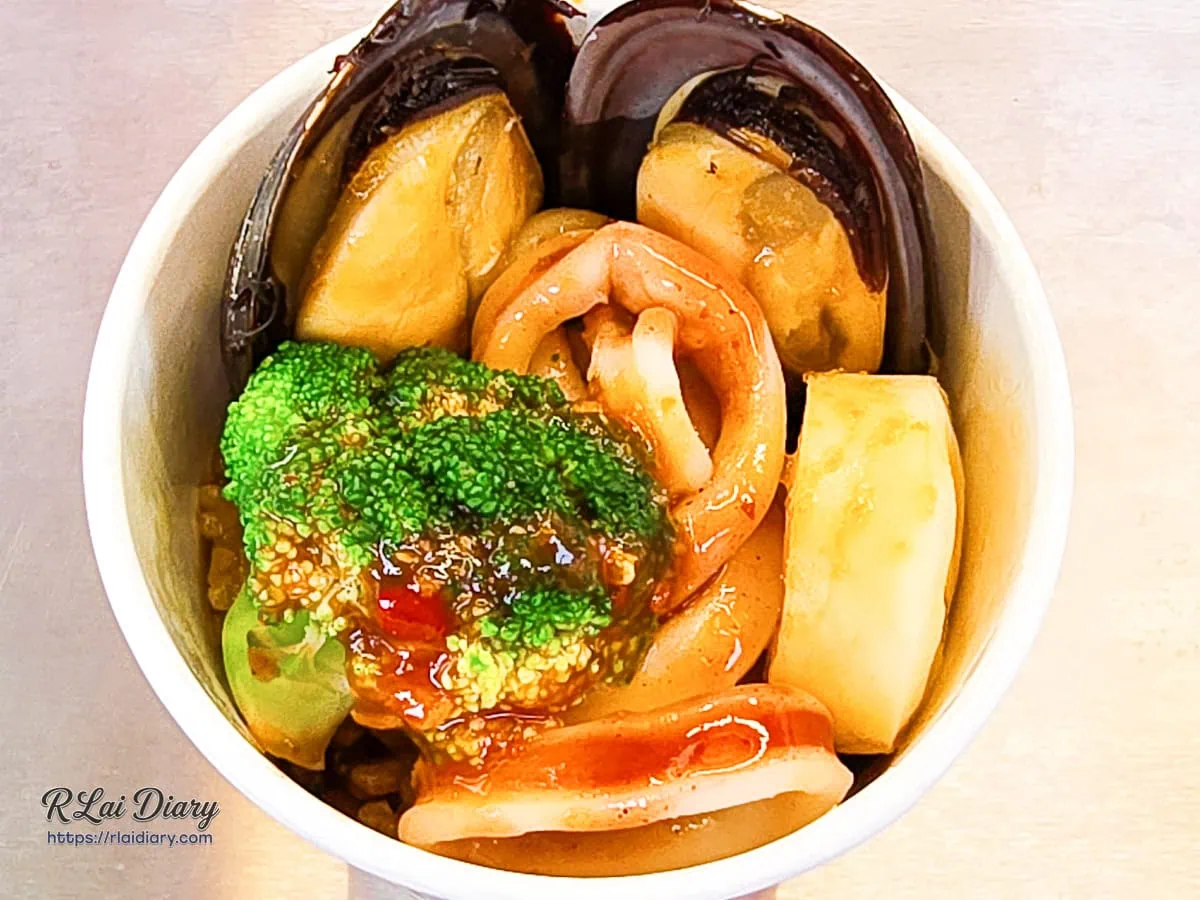 冠顗油飯一中店招牌蒜香海鮮油飯丼，杯裝設計呈現滿滿海鮮配料的視覺饗宴