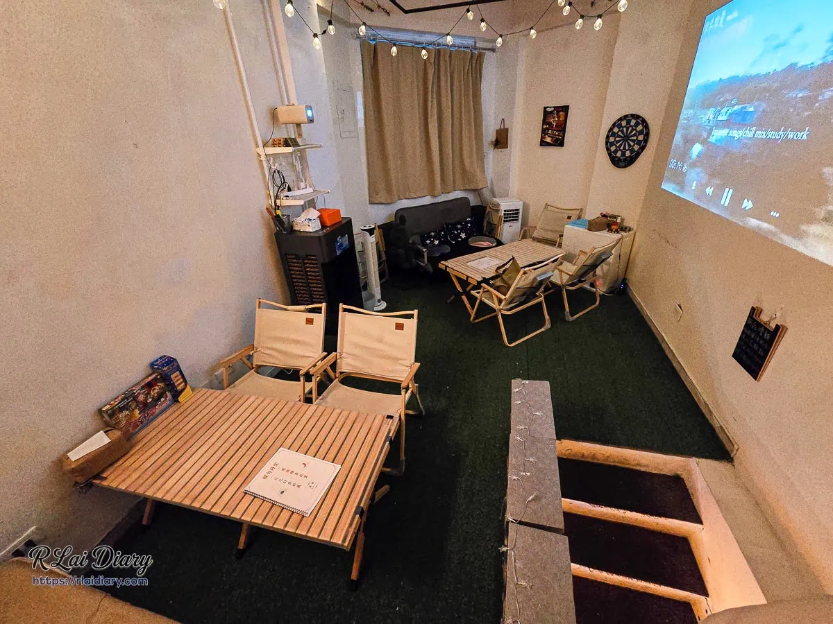 稷旬蒔堂居酒屋結合露營風桌椅與放鬆投影螢幕的用餐區